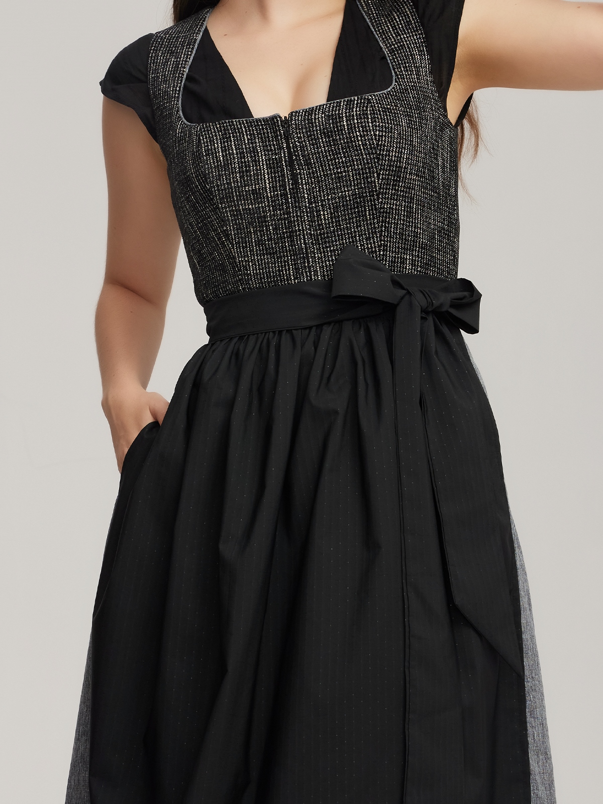 Ein elegantes rotes Dirndl mit schwarzer Schürze und Spitzenbluse